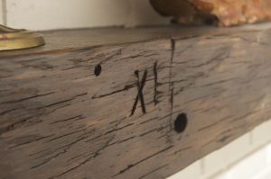 A close up of the Moore mantel focusing on the XI found carved in the original beam.